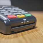 Commerciante che utilizza un POS per il pagamento, illustrando le nuove regole.