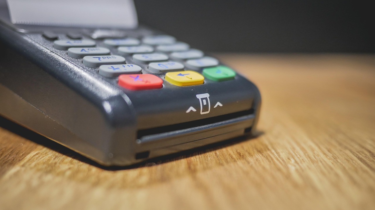 Commerciante che utilizza un POS per il pagamento, illustrando le nuove regole.