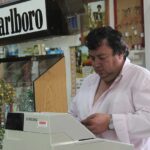 Un tabaccaio mostra un Gratta e Vinci vincente con un sorriso soddisfatto.